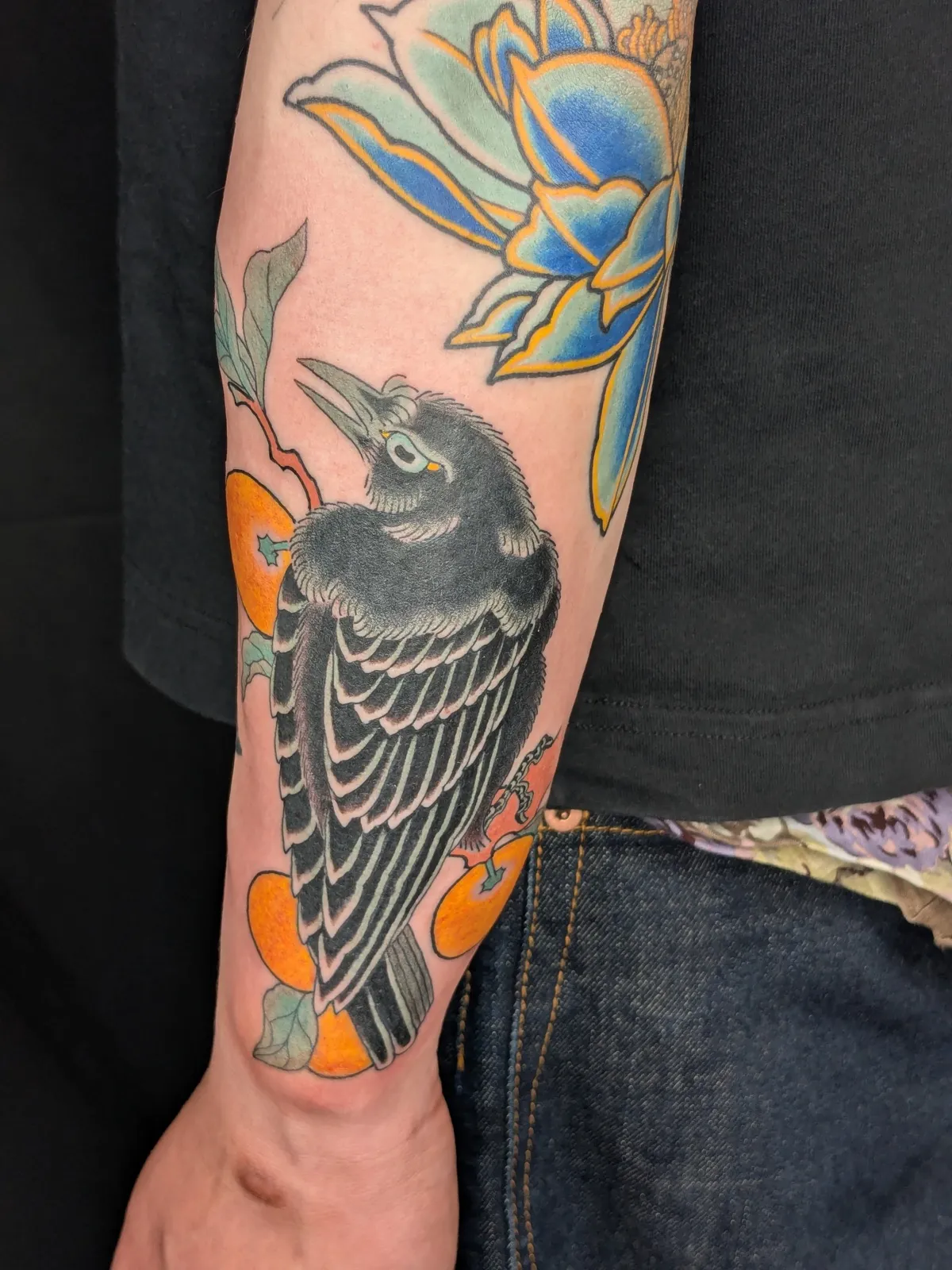 Crow and lotus tattoo on the forearm