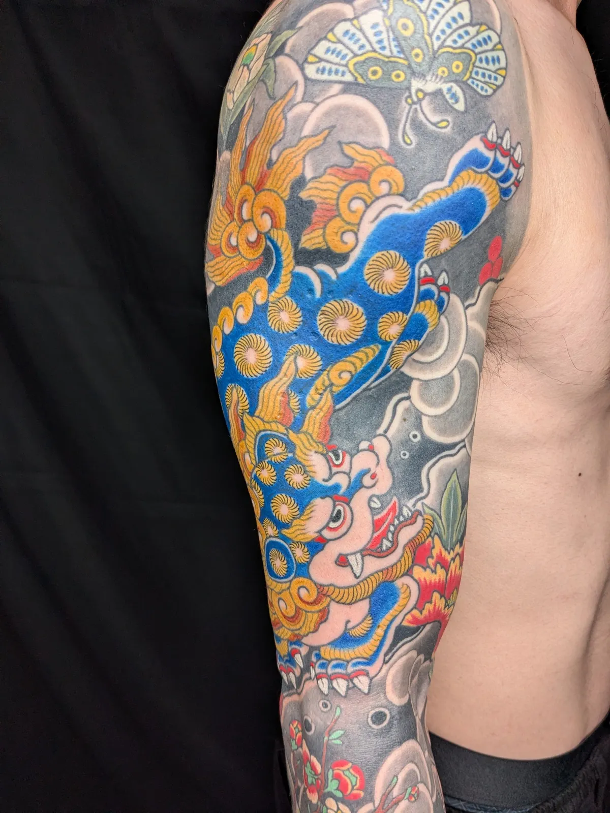Guardian lion and peony tattoo on the upper arm